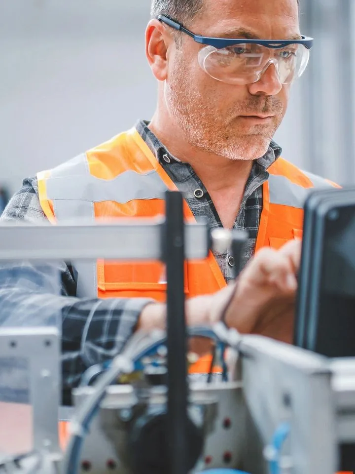 Industrial worker operating precision measurement equipment on the factory floor